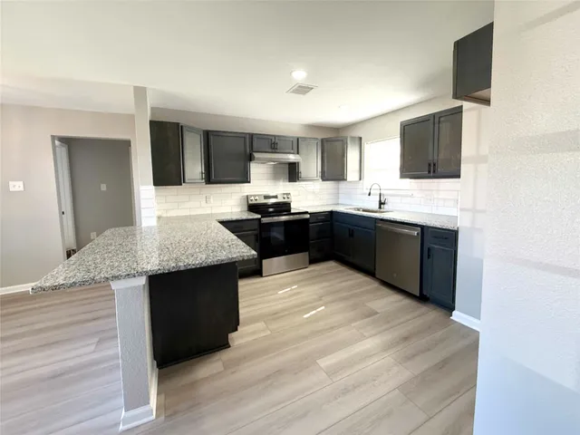 a kitchen with granite countertop sink stove and cabinets