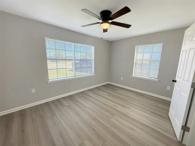 an empty room with wooden floor and windows