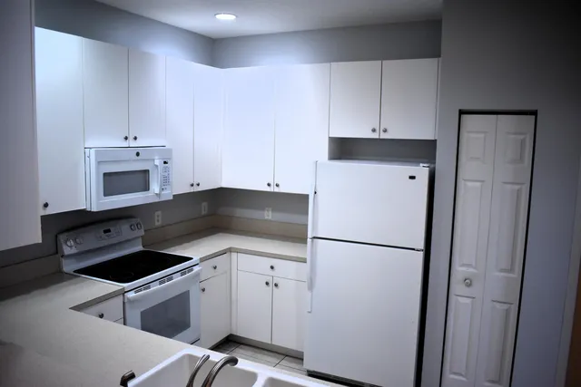 a kitchen with white cabinets and white appliances