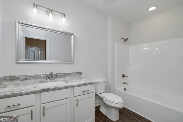 an empty room with wooden floor and ceiling fan