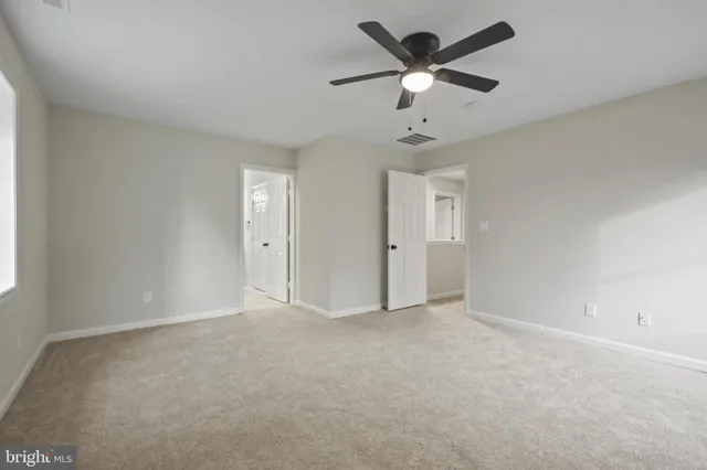 an empty room with chandelier fan and windows