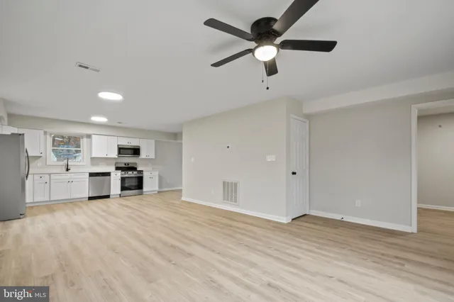 a view of a kitchen with furniture a ceiling fan and wooden floor