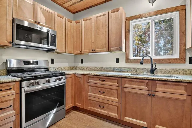 a kitchen with stainless steel appliances granite countertop a stove microwave and sink