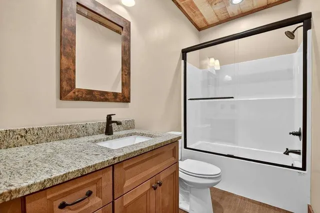 a bathroom with a granite countertop sink mirror vanity and toilet