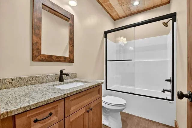a bathroom with a granite countertop sink mirror vanity and toilet