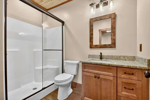 a bathroom with a granite countertop sink toilet and shower