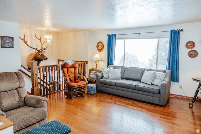 322 Bailey Creek Road Soda Springs, ID 83276 - Photo 6 of 32 Spacious living area featuring wood-finish flooring, a large window, and a built-in wooden staircase with a balustrade