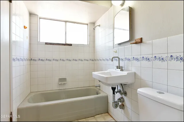 a bathroom with a sink a toilet a mirror and bathtub