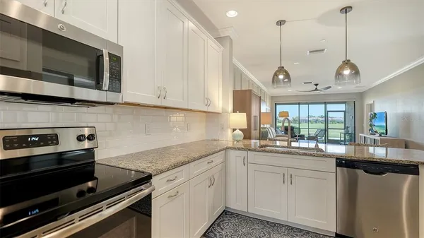 a kitchen with kitchen island granite countertop a refrigerator and a sink