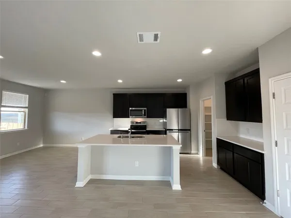 a view of kitchen with microwave stove refrigerator and cabinets