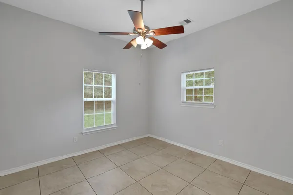an empty room with windows and fan
