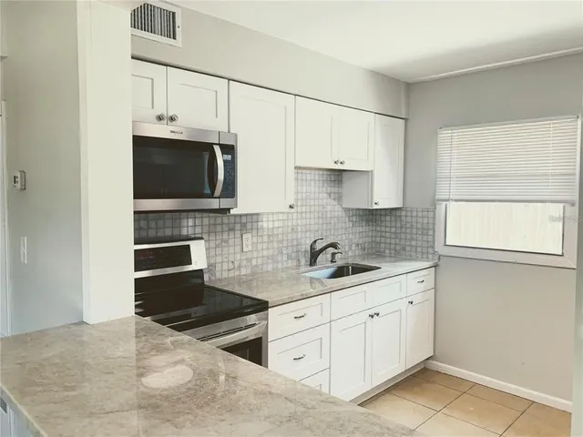 a kitchen with granite countertop white cabinets and black stainless steel appliances