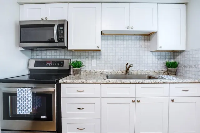 a kitchen with white cabinets stainless steel appliances and sink