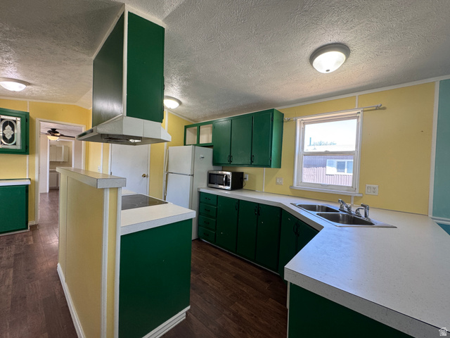 2491 Highway 89, Unit 315 Pleasant View, UT 84404 - Photo 23 of 34 Kitchen featuring wood-finish flooring, green cabinetry, a double basin stainless steel sink, and light-colored countertops