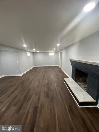 a view of an empty room with wooden floor fridge and a window