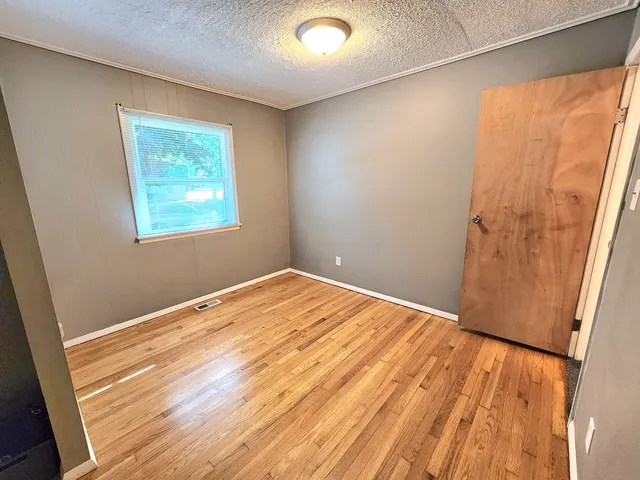 a view of empty room with wooden floor and fan