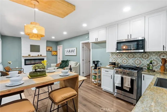 a kitchen with a stove a microwave a dining table and chairs with wooden floor