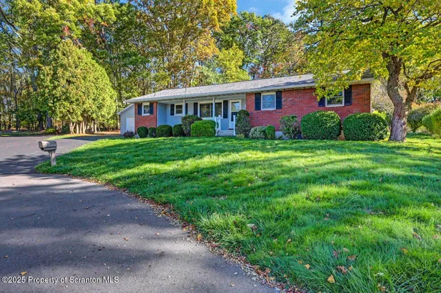 a view of a yard in front of a brick house with large windows