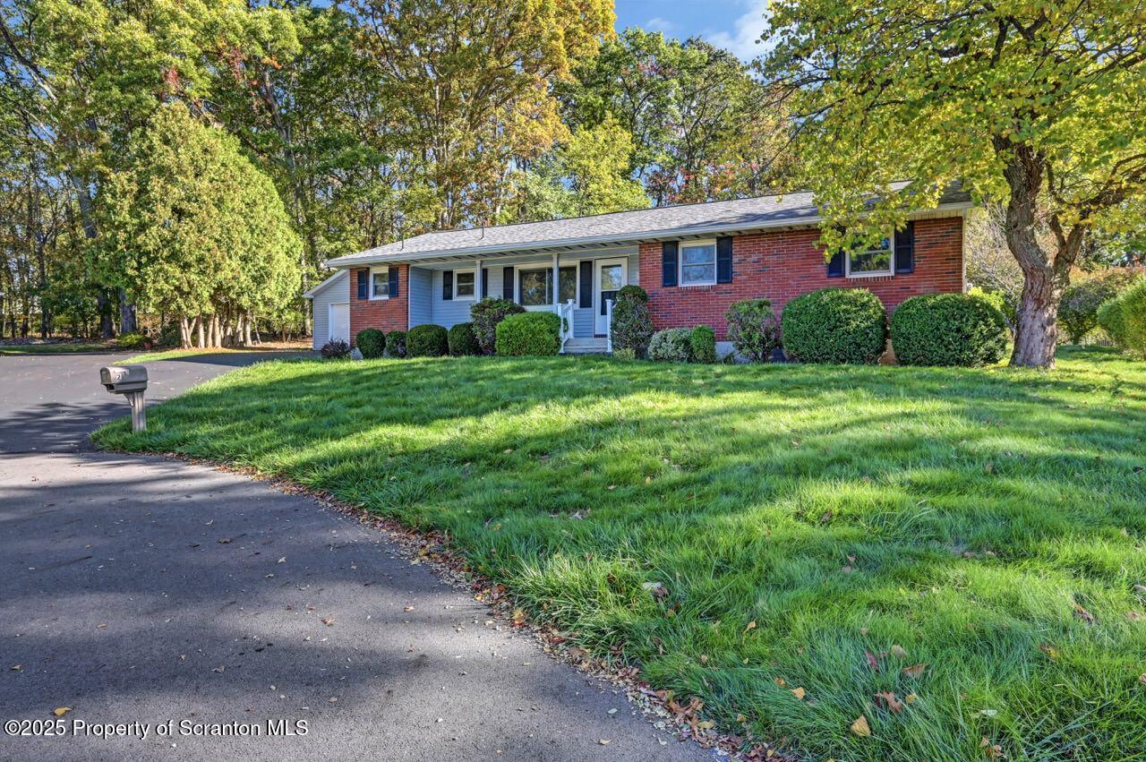 a view of a yard in front of a brick house with large windows