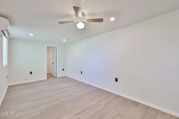 an empty room with a ceiling fan and wooden floor