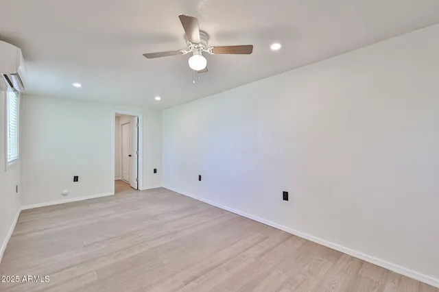 an empty room with a ceiling fan and wooden floor