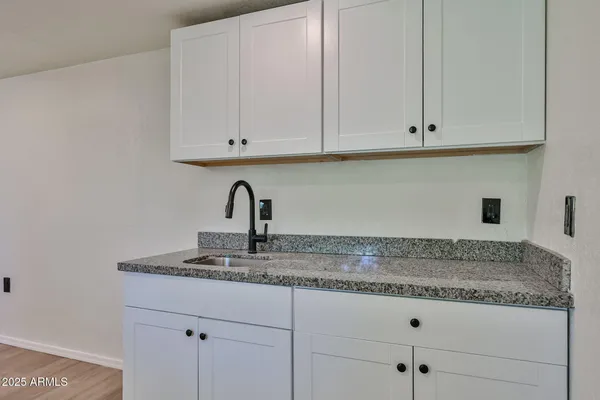 a kitchen with granite countertop white cabinets and a sink
