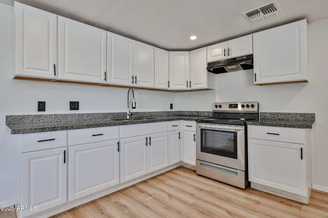 a kitchen with granite countertop white cabinets and white appliances