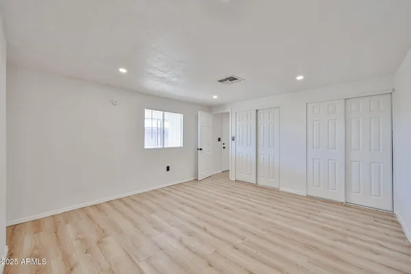 a view of an empty room with wooden floor and entryway