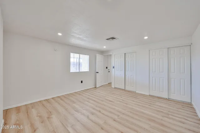a view of an empty room with wooden floor and entryway