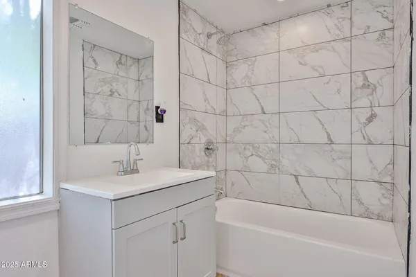 a bathroom with a bathtub sink vanity and shower