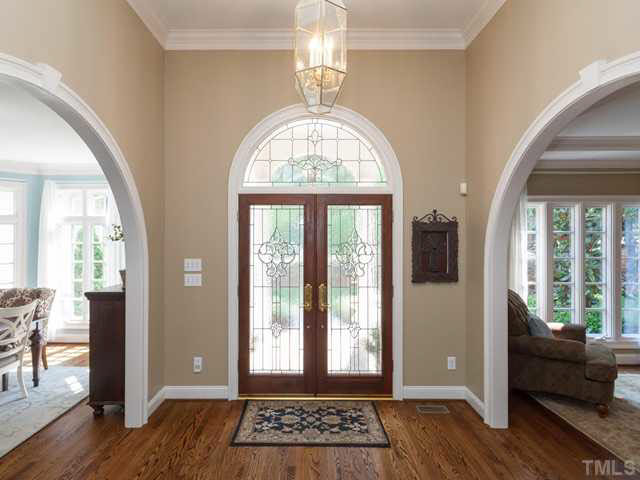 The freshly-painted foyer features crown molding, hardwood floors and graceful double French doors with leaded glass and an arched transom.