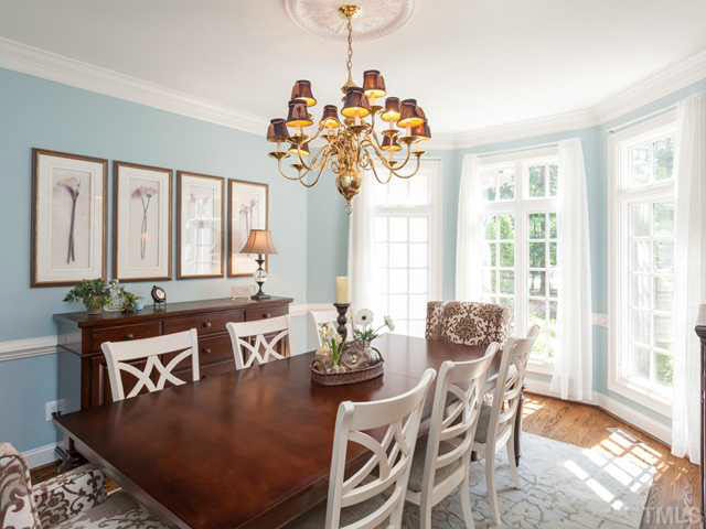The exquisite dining room offers hardwood floors, crown molding, chair railing, and a wide bay window with triple windows and transoms.