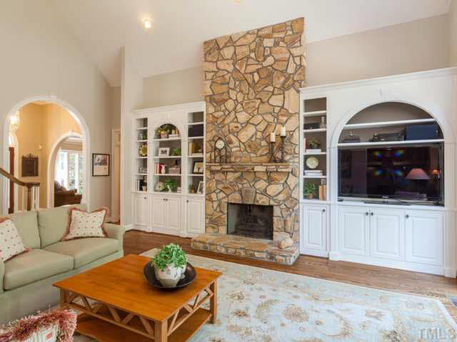 4612 White Chapel Way Raleigh, NC 27615 - Photo 8 of 25 The open family room enjoys a vaulted ceiling, hardwood floors, and a soaring stone fireplace that is framed by custom bookcases. The homeowners recently had a carpenter rebuild the cabinet to the right to accommodate a large flat screen TV.