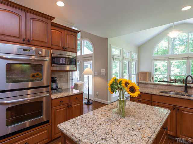 4612 White Chapel Way Raleigh, NC 27615 - Photo 9 of 25 The remodeled kitchen offers granite counters, a work island, and stainless appliances that includes double ovens and a microwave.