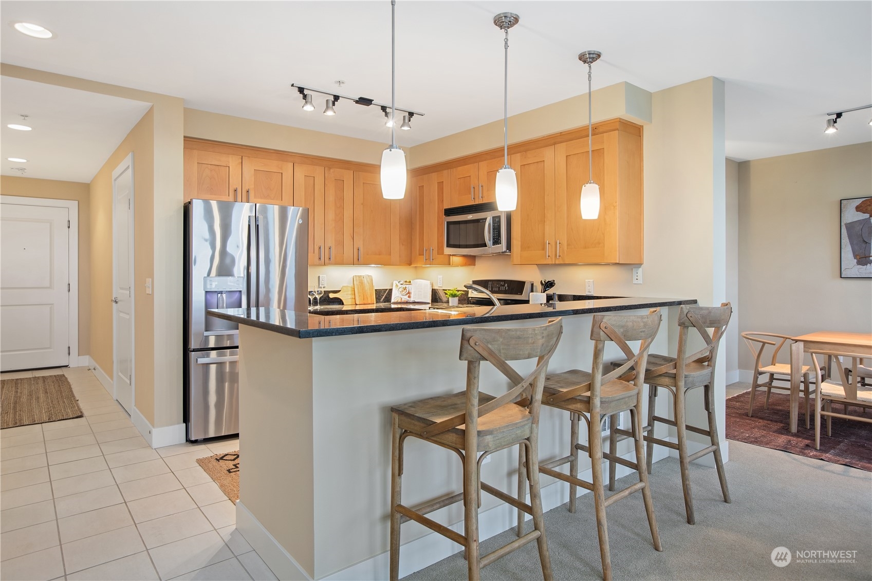 51 Pine Street, Unit 104 Edmonds, WA 98020 - Photo 10 of 40 a kitchen with stainless steel appliances granite countertop a refrigerator a stove a sink dishwasher and a dining table with wooden floor