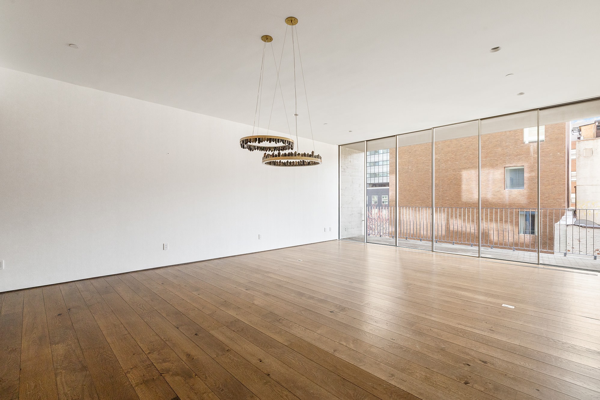 a view of an empty room with wooden floor and windows