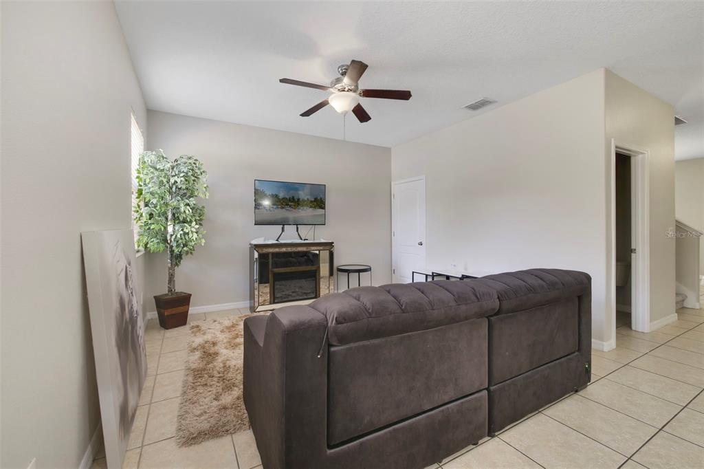 1209 Seburn Road Apopka, FL 32703 - Photo 5 of 25 a living room with furniture a chandelier a fireplace and a flat screen tv