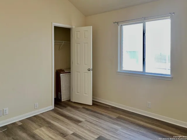a view of an empty room with wooden floor and closet