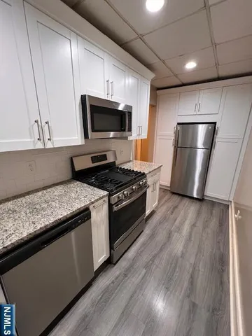 a kitchen with stainless steel appliances granite countertop a stove a refrigerator and a microwave