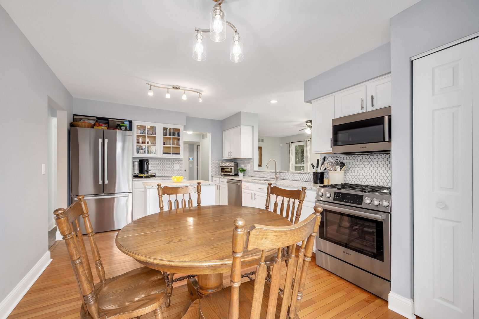772 Rebecca Lane Bolingbrook, IL 60440 - Photo 12 of 27 a kitchen with stainless steel appliances granite countertop a stove a refrigerator a microwave oven a dining table and chairs with wooden floor