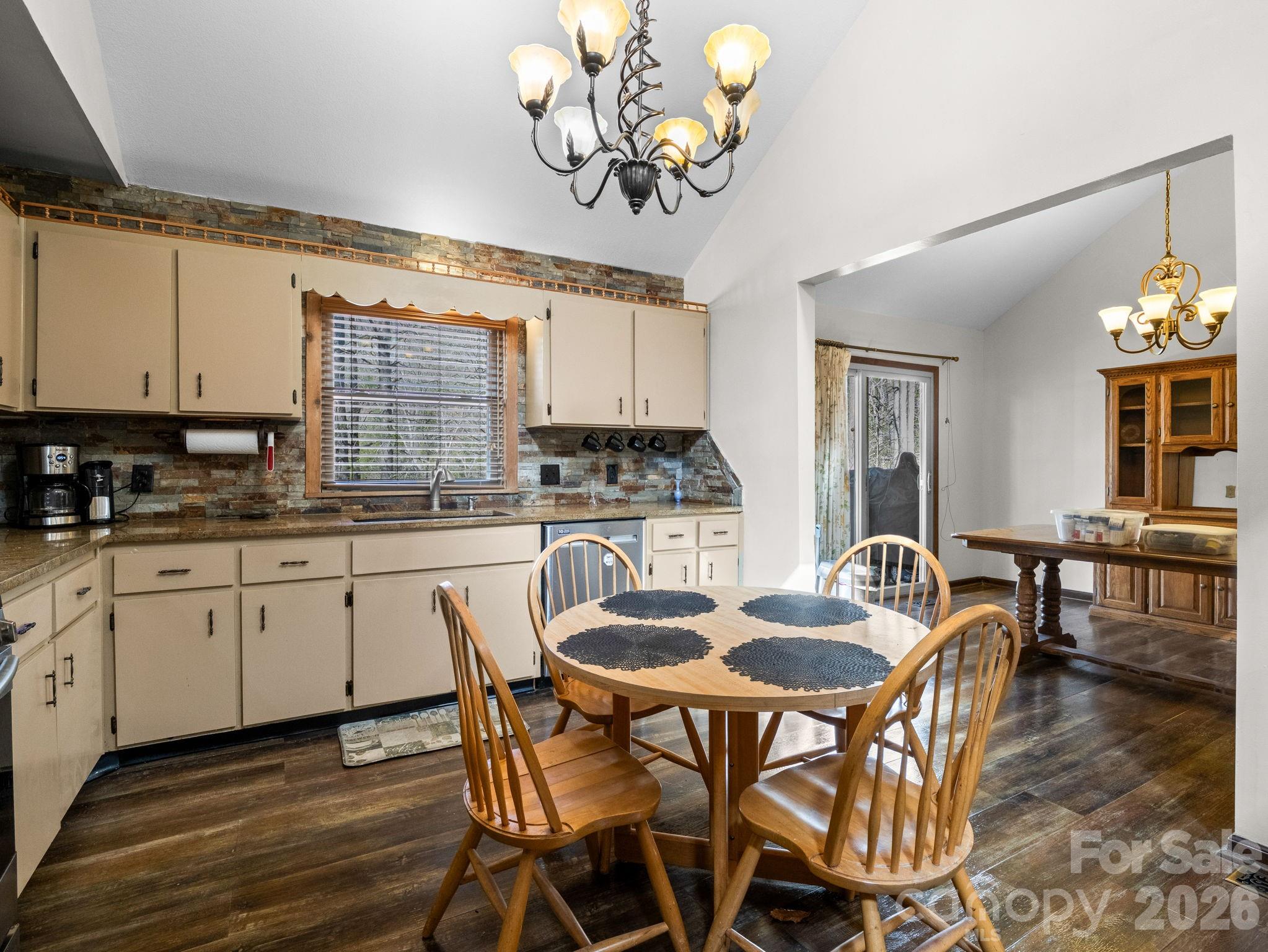 111 Buckeye Road Lake Lure, NC 28746 - Photo 11 of 48 a kitchen with stainless steel appliances granite countertop a stove a sink dishwasher a dining table and chairs with wooden floor