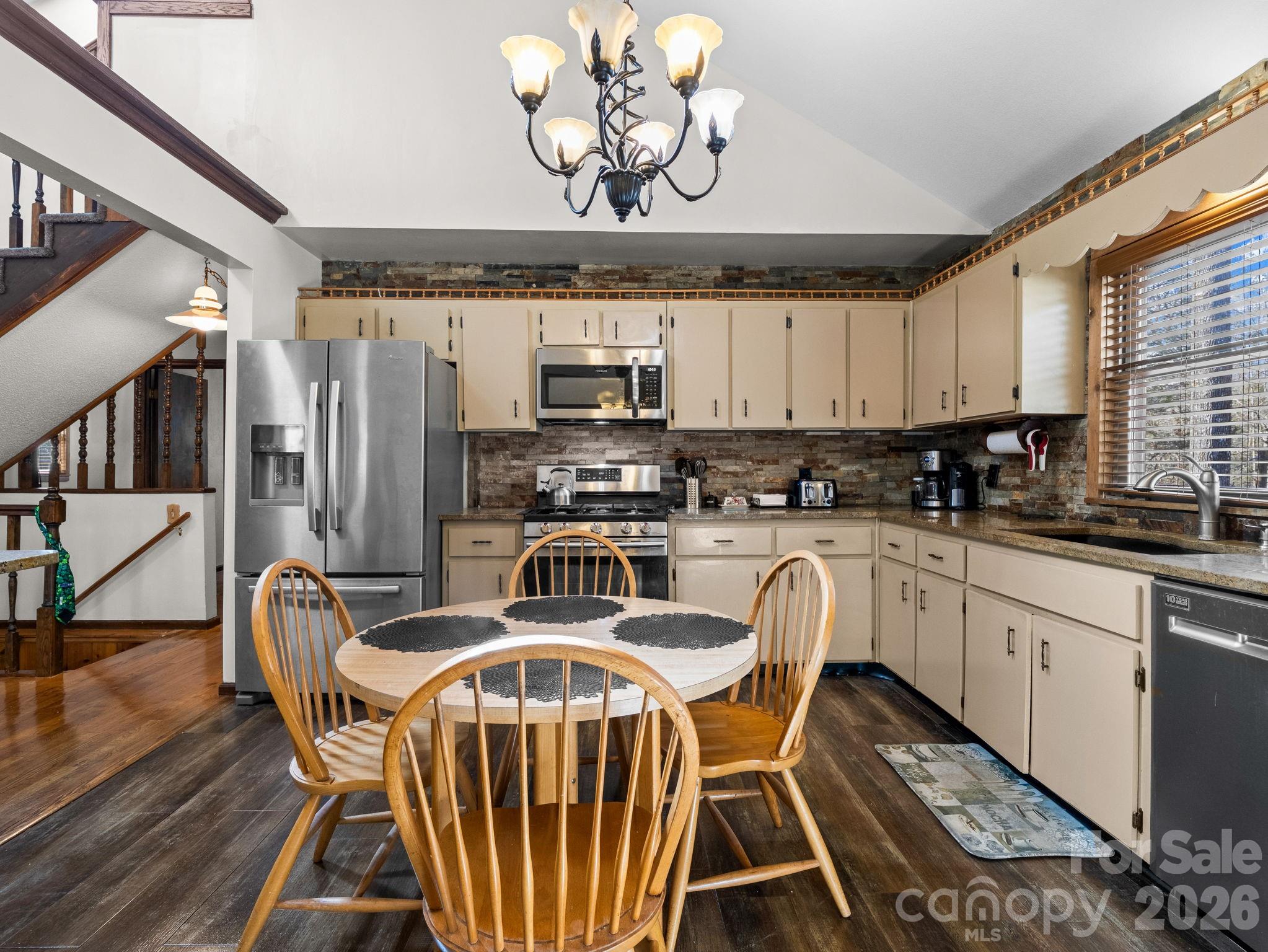 111 Buckeye Road Lake Lure, NC 28746 - Photo 10 of 48 a kitchen with stainless steel appliances granite countertop a stove a refrigerator a kitchen island a dining table and chairs with wooden floor