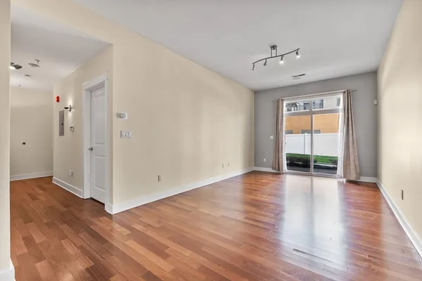 a view of an empty room with wooden floor and a window