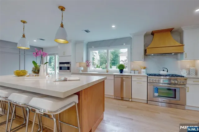 a kitchen with stainless steel appliances granite countertop a sink a stove and a wooden floors