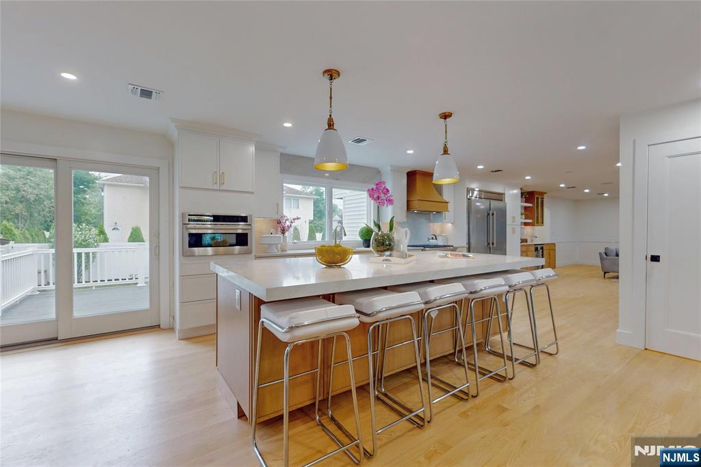 415 Bailey Road Paramus, NJ 07652 - Photo 13 of 44 a kitchen with stainless steel appliances granite countertop a kitchen island a stove a refrigerator a sink a dining table and chairs with wooden floor