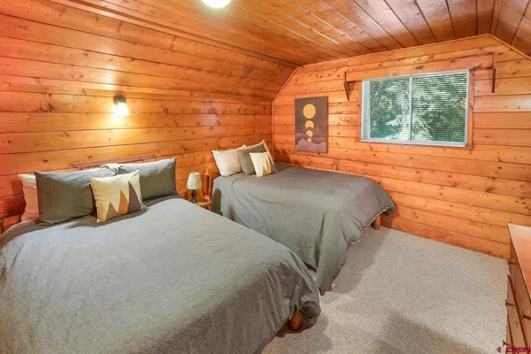 a bedroom with two beds and a potted plant