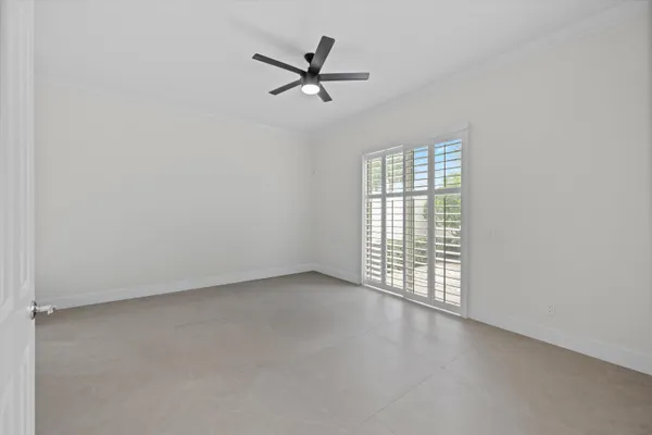 an empty room with ceiling fan and windows
