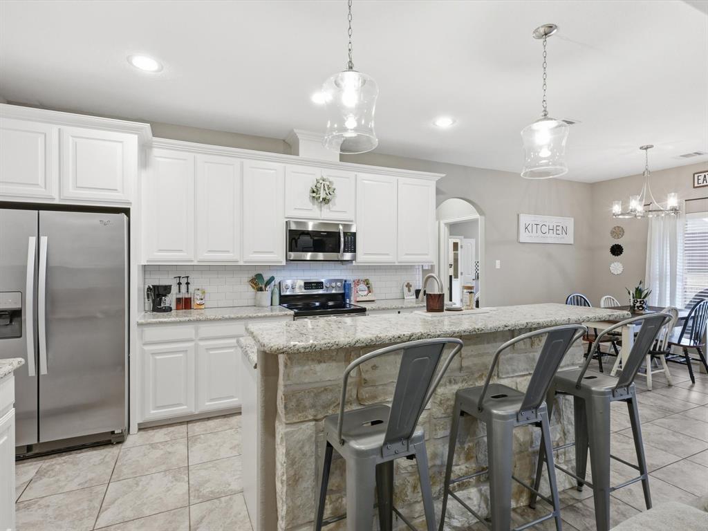 810 Chestnut Grove Drive Cleburne, TX 76033 - Photo 24 of 40 a kitchen with stainless steel appliances granite countertop a sink a stove a refrigerator cabinets and chairs