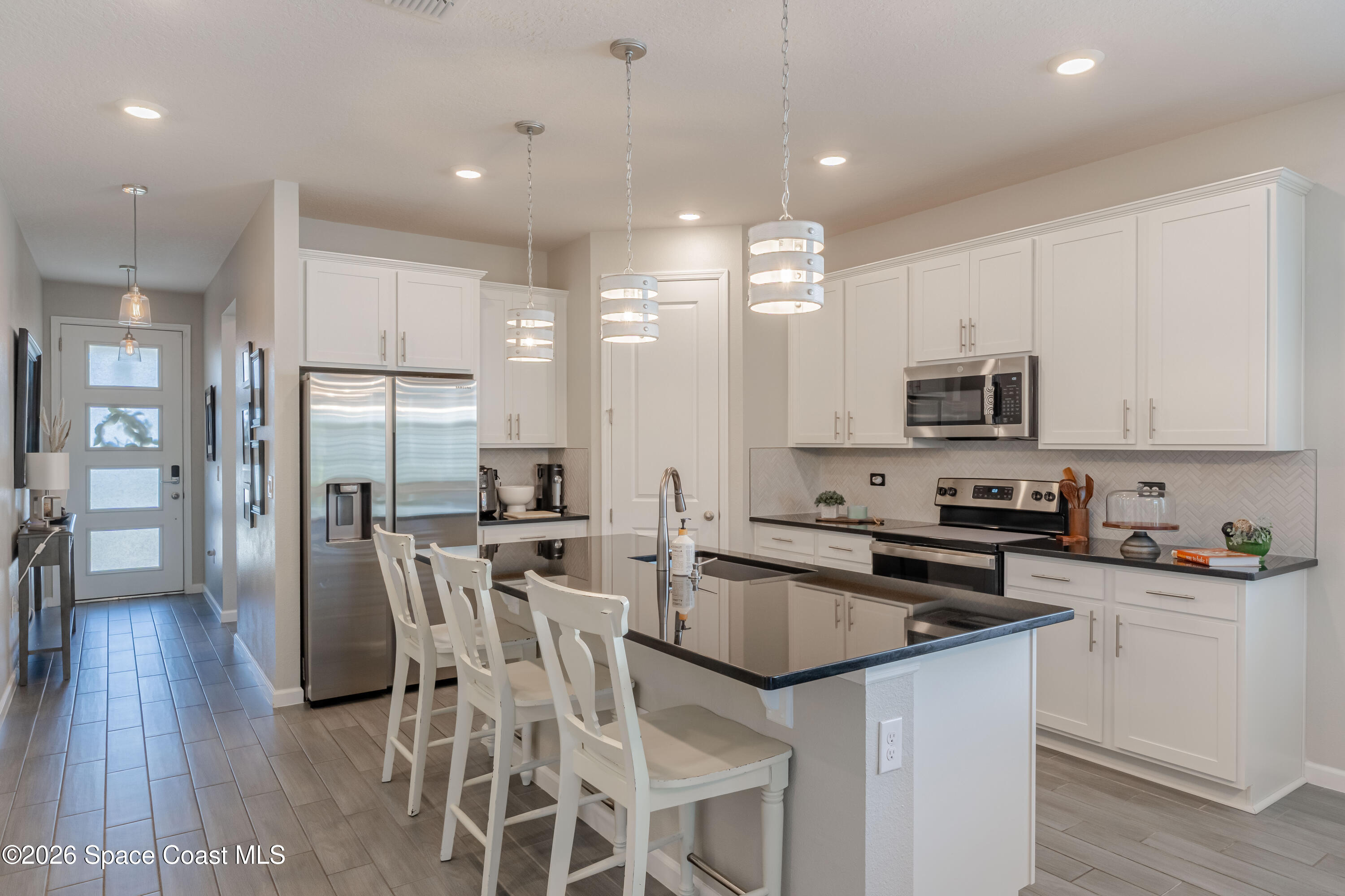 4342 Southern Vista Loop St. Cloud, FL 34772 - Photo 4 of 30 a kitchen with stainless steel appliances granite countertop a refrigerator a stove top oven a sink dishwasher and white cabinets with wooden floor