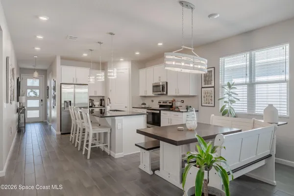a dining room with stainless steel appliances kitchen island granite countertop a table chairs and a refrigerator
